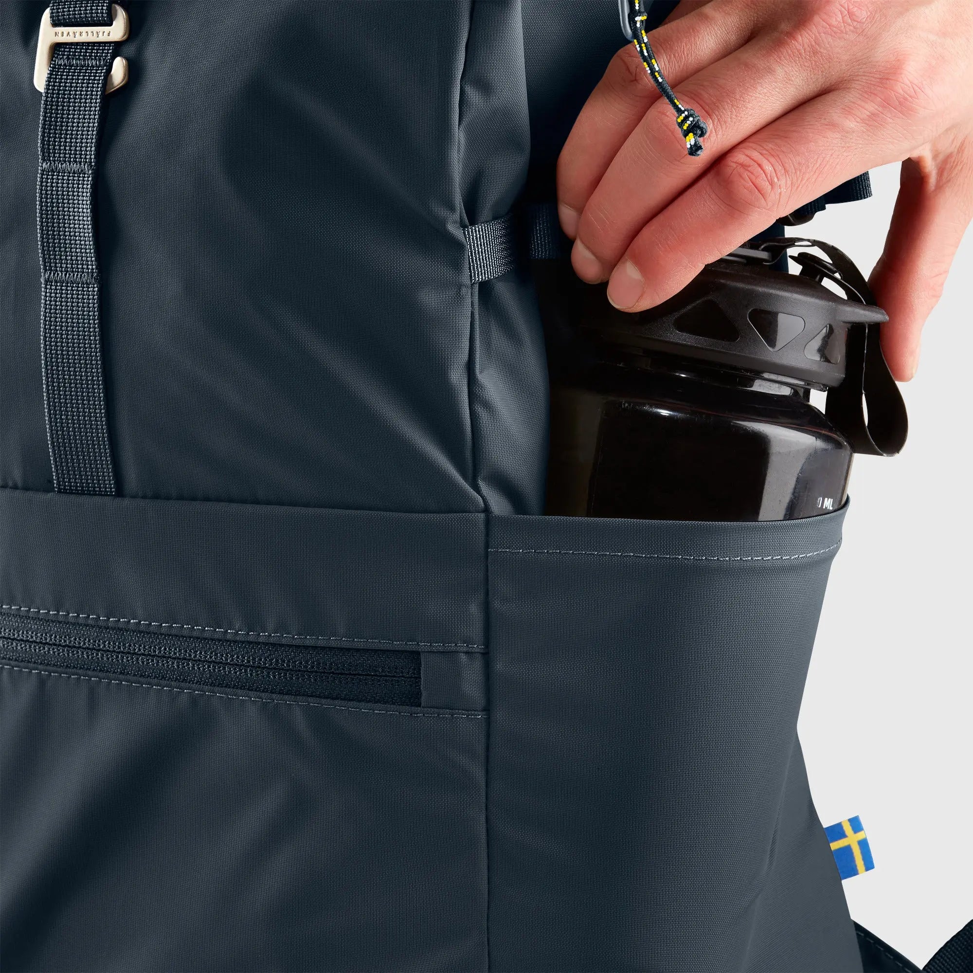 Fjallraven High Coast Foldsack 24, side pocket holding a water bottle, shown in Navy; shared feature image