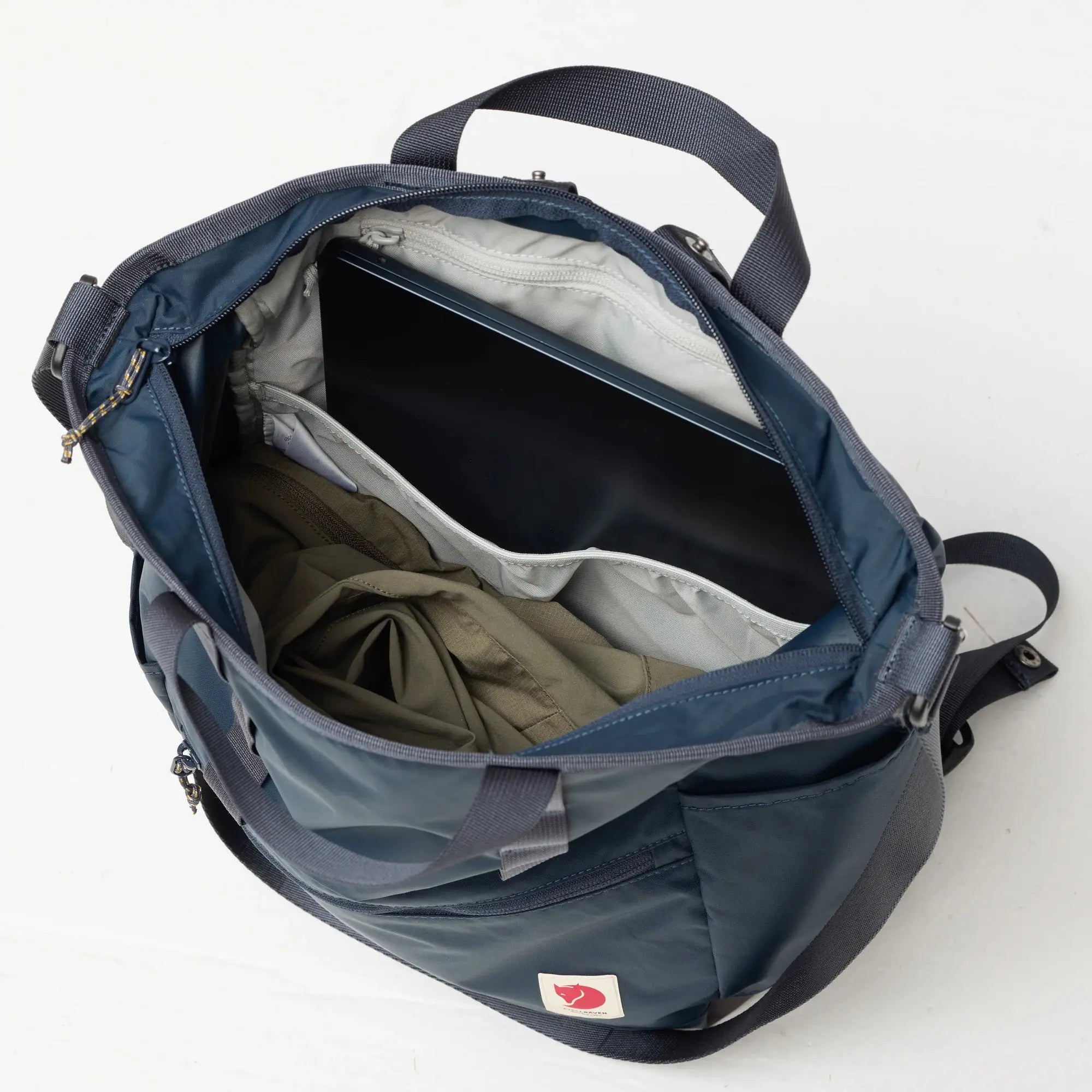 Fjallraven High Coast Totepack, open main compartment with a laptop and jacket, shown in Navy; shared feature image