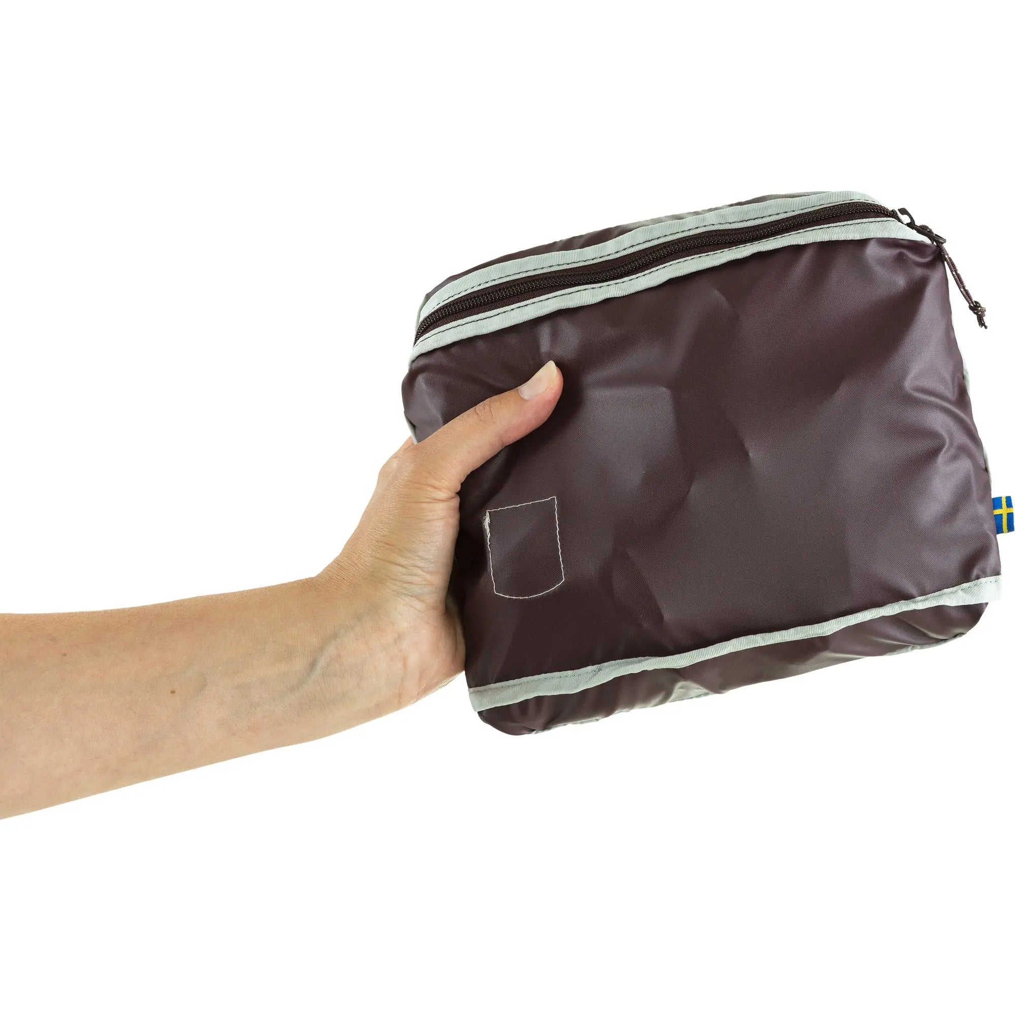 Fjallraven High Coast Totepack, pack folded into its pocket and held in one hand, shown in Blackberry; shared feature image