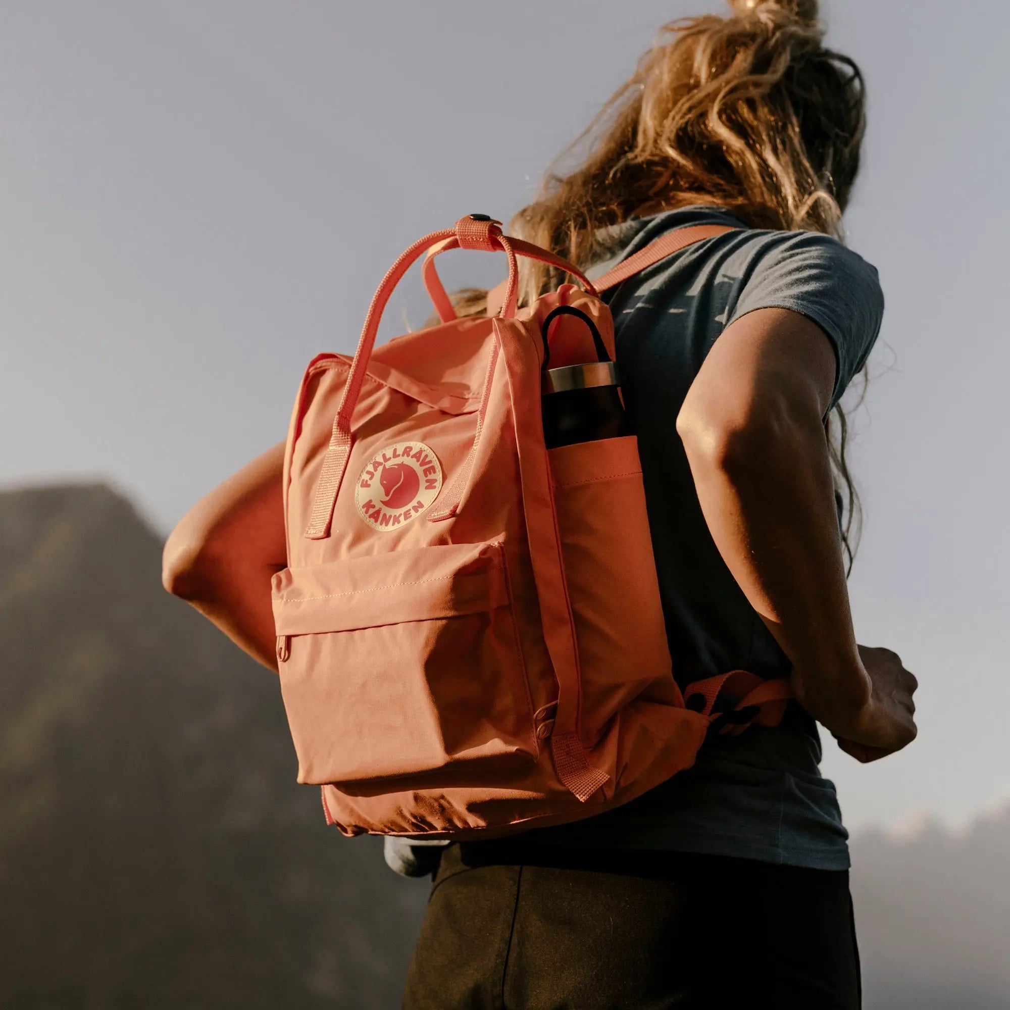 Fjallraven Kanken Backpack, backpack carry outdoors, shown in salmon pink; shared feature image