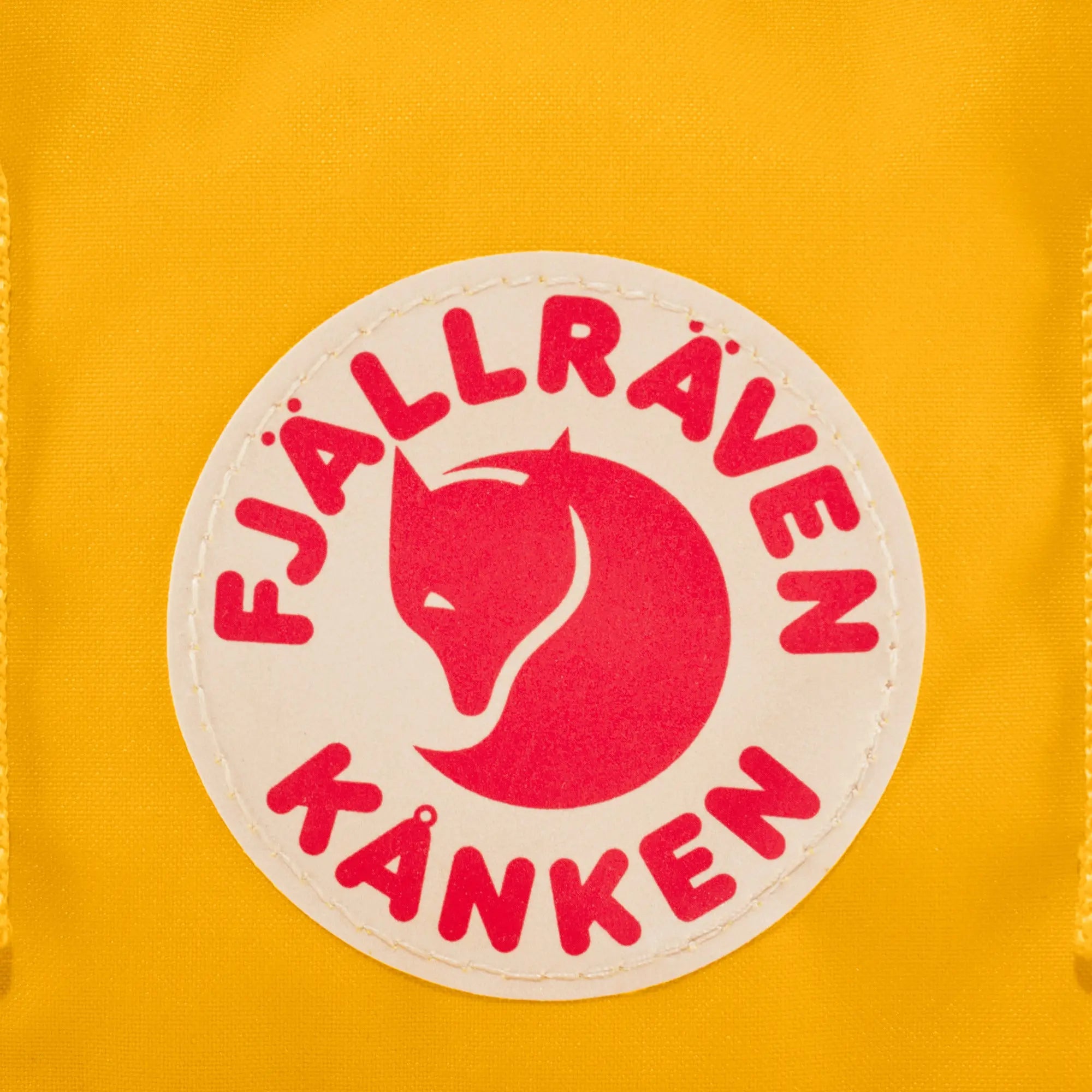 Fjallraven Kanken Mini Backpack, round logo detail, shown in Warm Yellow; shared feature image