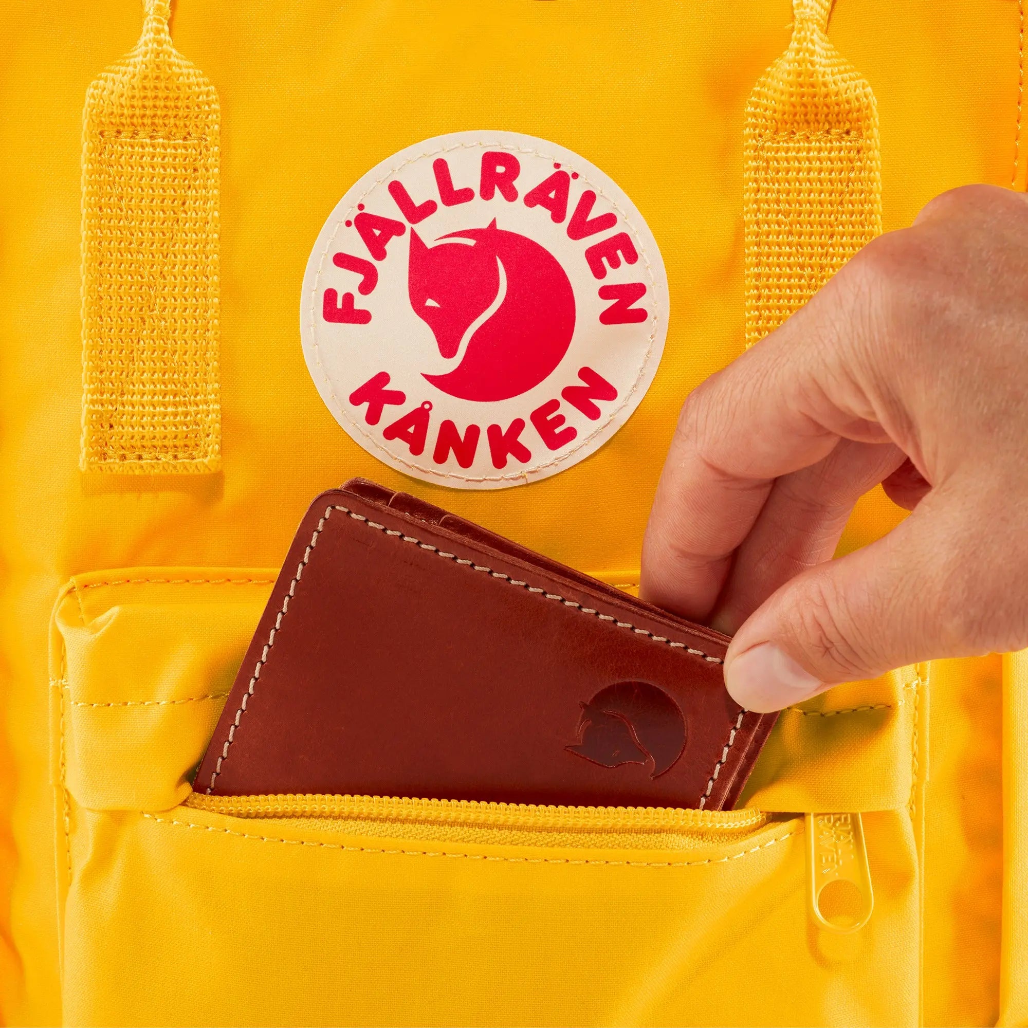 Fjallraven Kanken Mini Backpack, front pocket holding a wallet, shown in Warm Yellow; shared feature image
