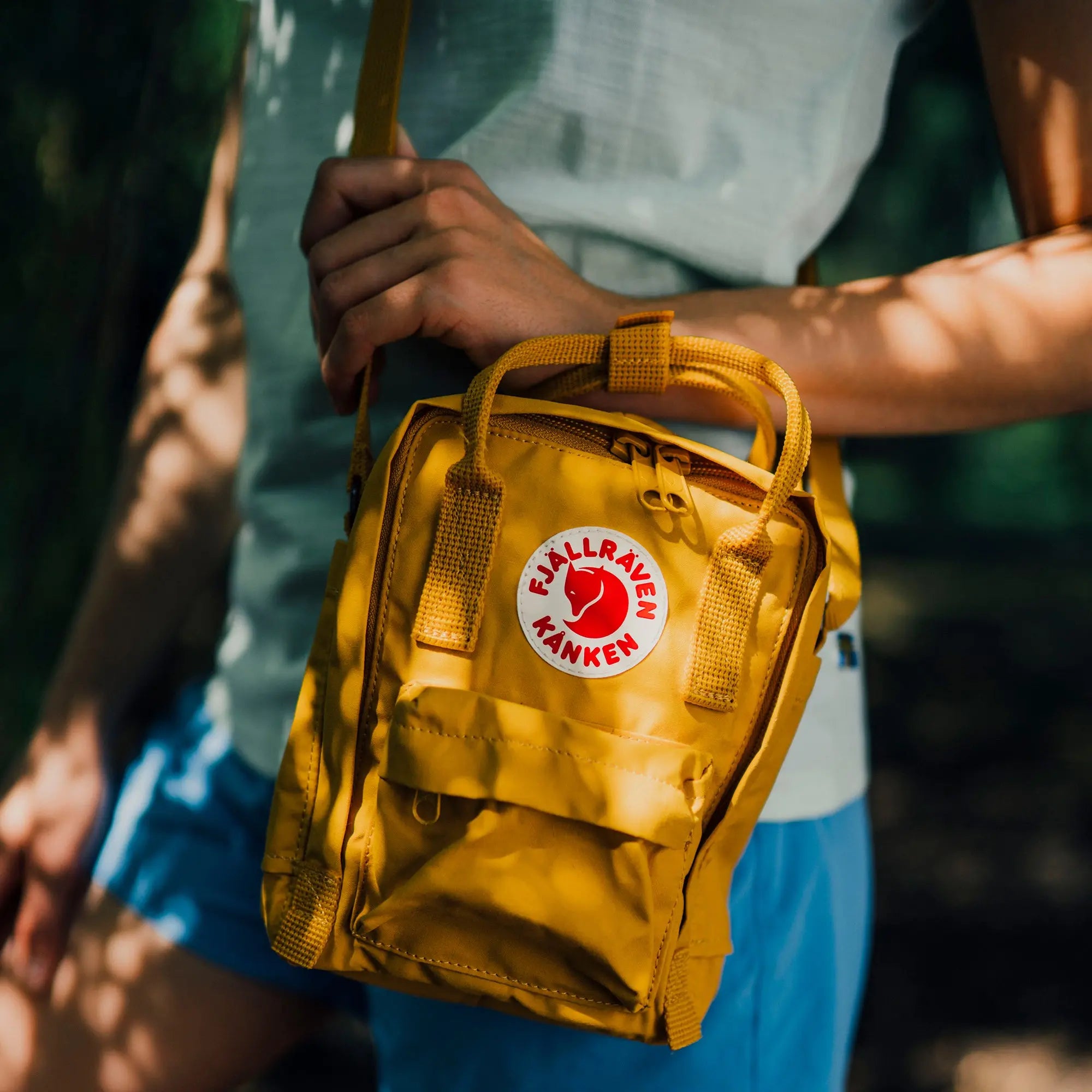 Fjallraven Kanken Sling, carried outdoors by a model, shown in yellow; shared feature image