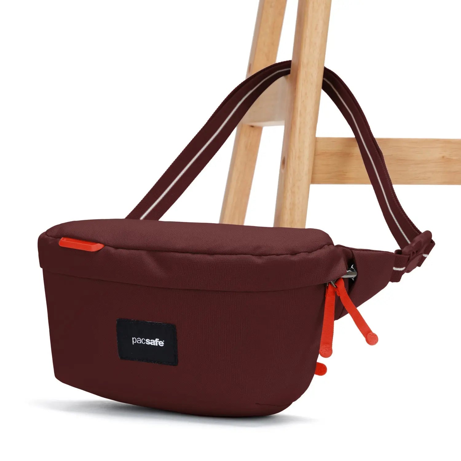 Pacsafe GO Sling Pack, Garnet Red — anchored around a chair