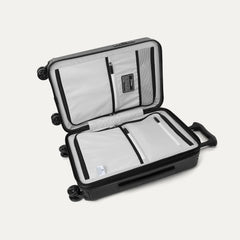 Interior packing view of the Travelpro Platinum Elite Compact Carry-On Hardside Spinner in Aviator Navy, featuring dual zippered divider panels and ECOFAB™ lining made from 100% recycled plastic bottles.