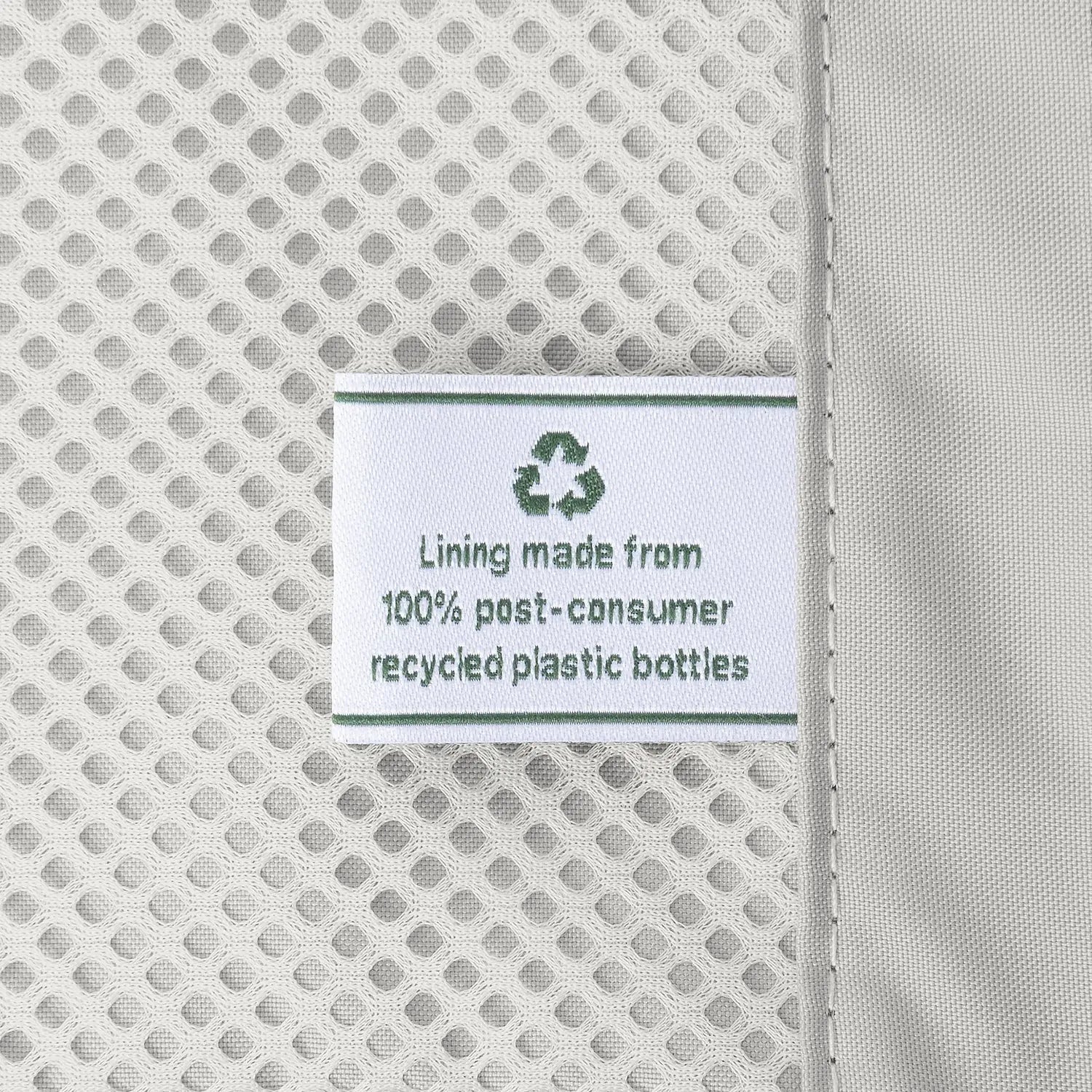 Macro detail of the ECOFAB™ interior lining on the Travelpro Platinum Elite Compact Carry-On Hardside Spinner in Aviator Navy, featuring a tag that reads "Lining made from 100% post-consumer recycled plastic bottles."
