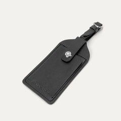 close-up of the premium black leather luggage tag with the embossed travelpro logo, featuring a secure buckle strap and a privacy flap for contact information, included with the hardside spinner.