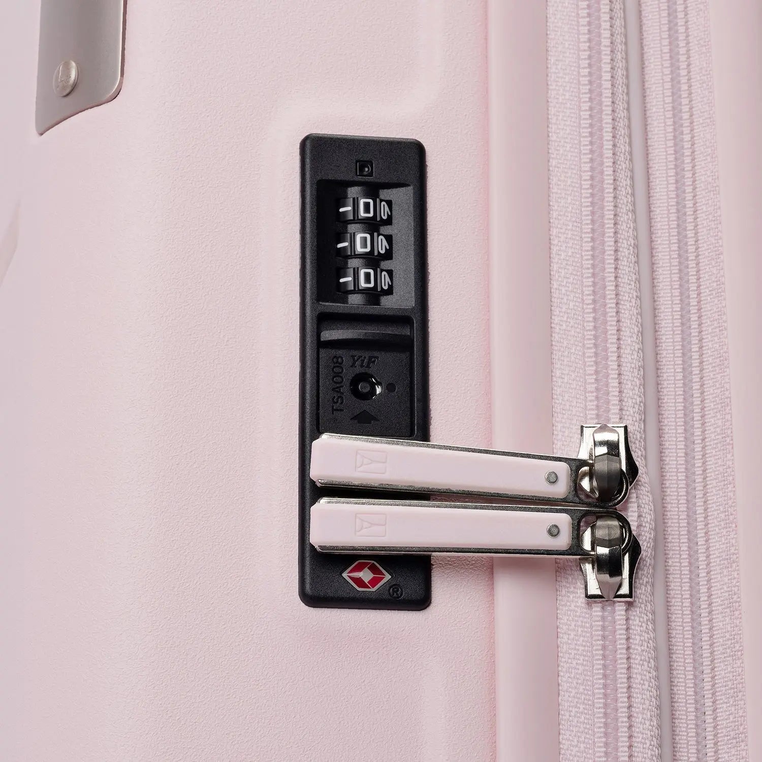 Close-up view of the light pink Travelpro Platinum Elite Next Gen Powder Pink Suitcase, highlighting the black TSA-approved combination lock, silver metal zipper pulls with pink leather accents, and white zipper teeth against an off-white background.