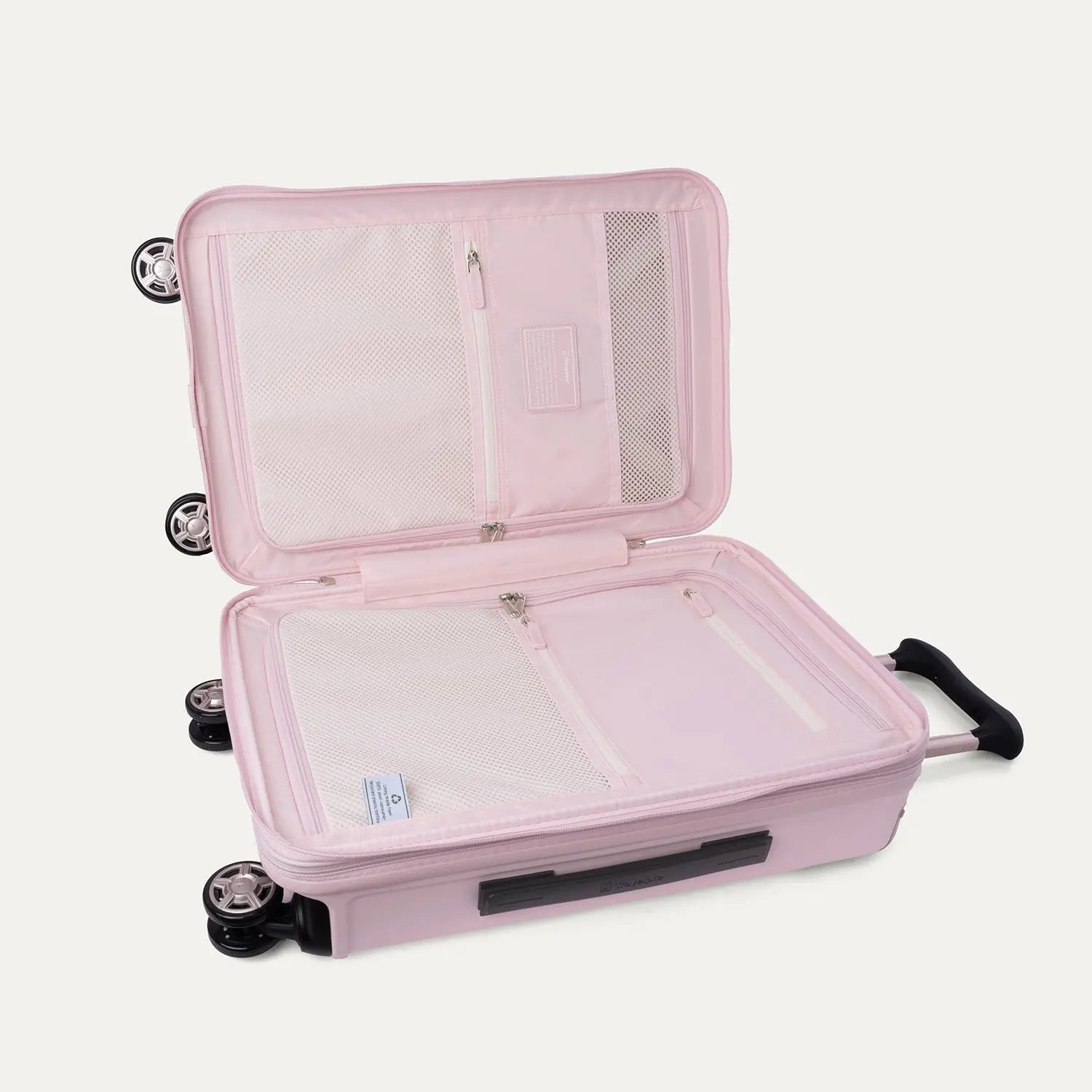 Open interior view of the light pink Travelpro Platinum Elite Next Gen Powder Pink Suitcase, showing the main packing compartment with zippered dividers, mesh pockets, and multi-directional spinner wheels against a clean off-white background.
