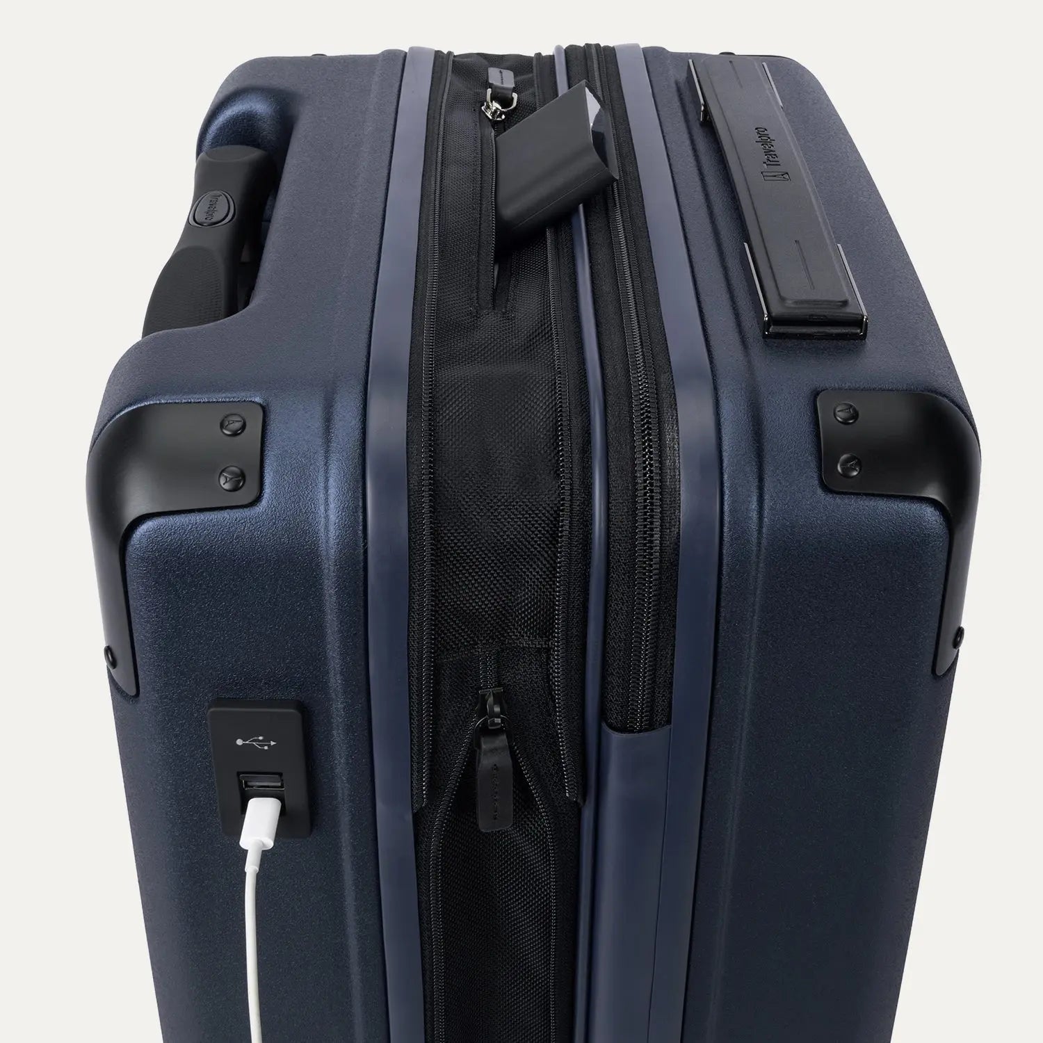 Close-up of the external charging ports on the Travelpro Platinum Elite Carry-On Hardside Spinner in Aviator Navy, showing a white cable plugged into the USB-A port and a power bank tucked into the dedicated battery sleeve within the expansion gusset.