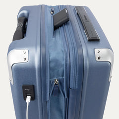 Close-up of the external charging ports on the Travelpro Platinum Elite Carry-On Hardside Spinner in Dark Sky Blue, showing a cable plugged into the USB-A port next to a USB-C port and a power bank in the dedicated battery sleeve.