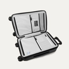 Interior packing view of the Travelpro Platinum Elite Carry-On Hardside Spinner in Jet Black, featuring dual zippered divider panels and the ECOFAB™ lining made from 100% recycled plastic bottles.