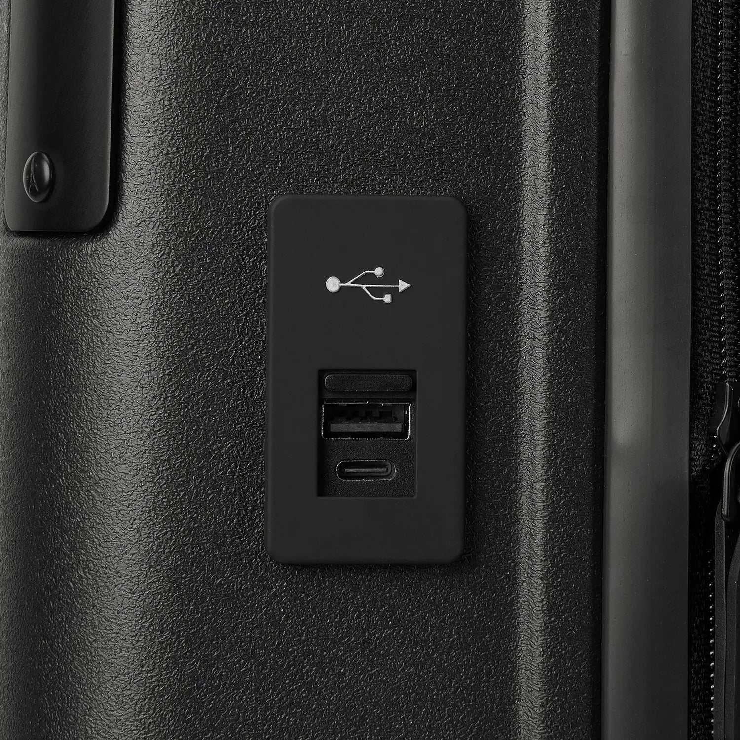 Macro detail view of the external USB-A and USB-C charging ports on the Travelpro Platinum Elite Carry-On Hardside Spinner in Jet Black, highlighting the integrated power connectivity for mobile devices.