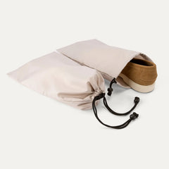 Close-up of the two removable drawstring shoe bags included with the Travelpro Platinum Elite Carry-On Hardside Spinner, showing a brown shoe partially inserted to demonstrate organizational use.