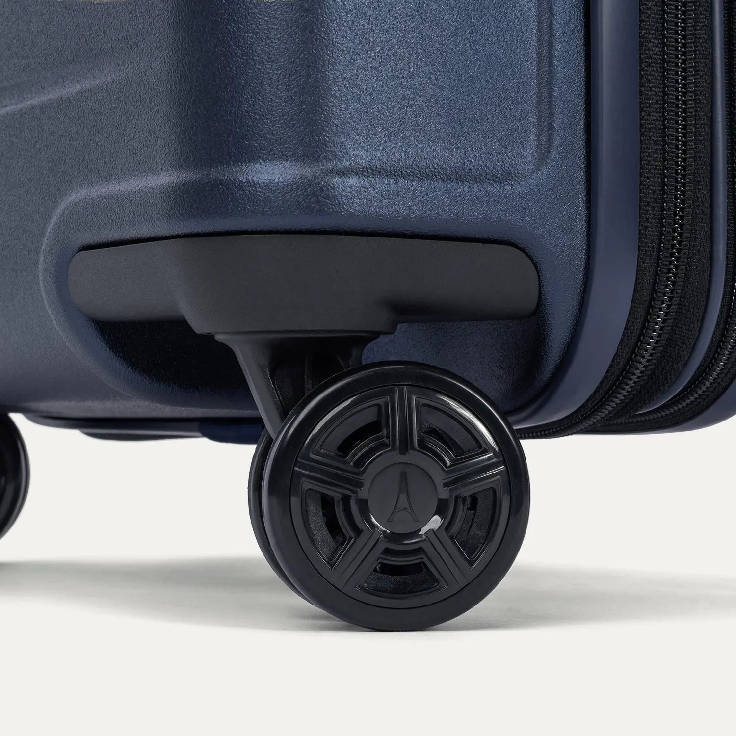 Close-up of the dual spinner wheels on the Travelpro Platinum Elite Medium Check-In Hardside Spinner in Aviator Navy, featuring the self-aligning MagnaTrac® technology and polished silver-tone wheel hubs.