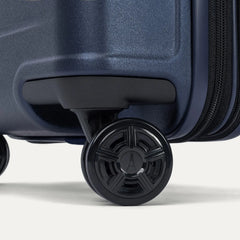 Close-up of the dual spinner wheels on the Travelpro Platinum Elite Medium Check-In Hardside Spinner in Aviator Navy, featuring the self-aligning MagnaTrac® technology and polished silver-tone wheel hubs.