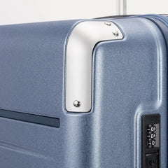 Close-up detail of the Travelpro Platinum Elite Medium Check-In Hardside Spinner in Dark Sky Blue, showing the integrated TSA-approved combination lock and protective polished aluminum corner armor.