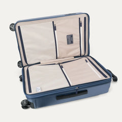 Interior packing view of the Travelpro Platinum Elite Medium Check-In Hardside Spinner in Dark Sky Blue, featuring dual zippered divider panels and the ECOFAB™ lining made from 100% recycled plastic bottles.