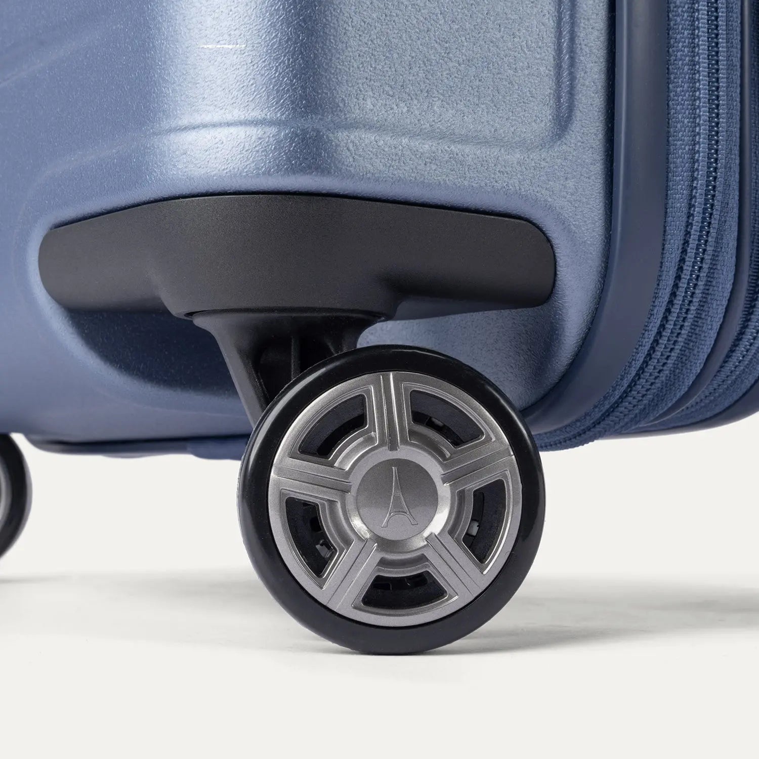 Close-up of the dual spinner wheels on the Travelpro Platinum Elite Medium Check-In Hardside Spinner in Dark Sky Blue, featuring the self-aligning MagnaTrac® technology and polished silver-tone wheel hubs.