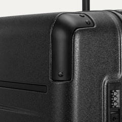 Close-up detail of the Travelpro Platinum Elite Medium Check-In Hardside Spinner in Jet Black, showing the integrated TSA-approved combination lock and protective polished aluminum corner armor.