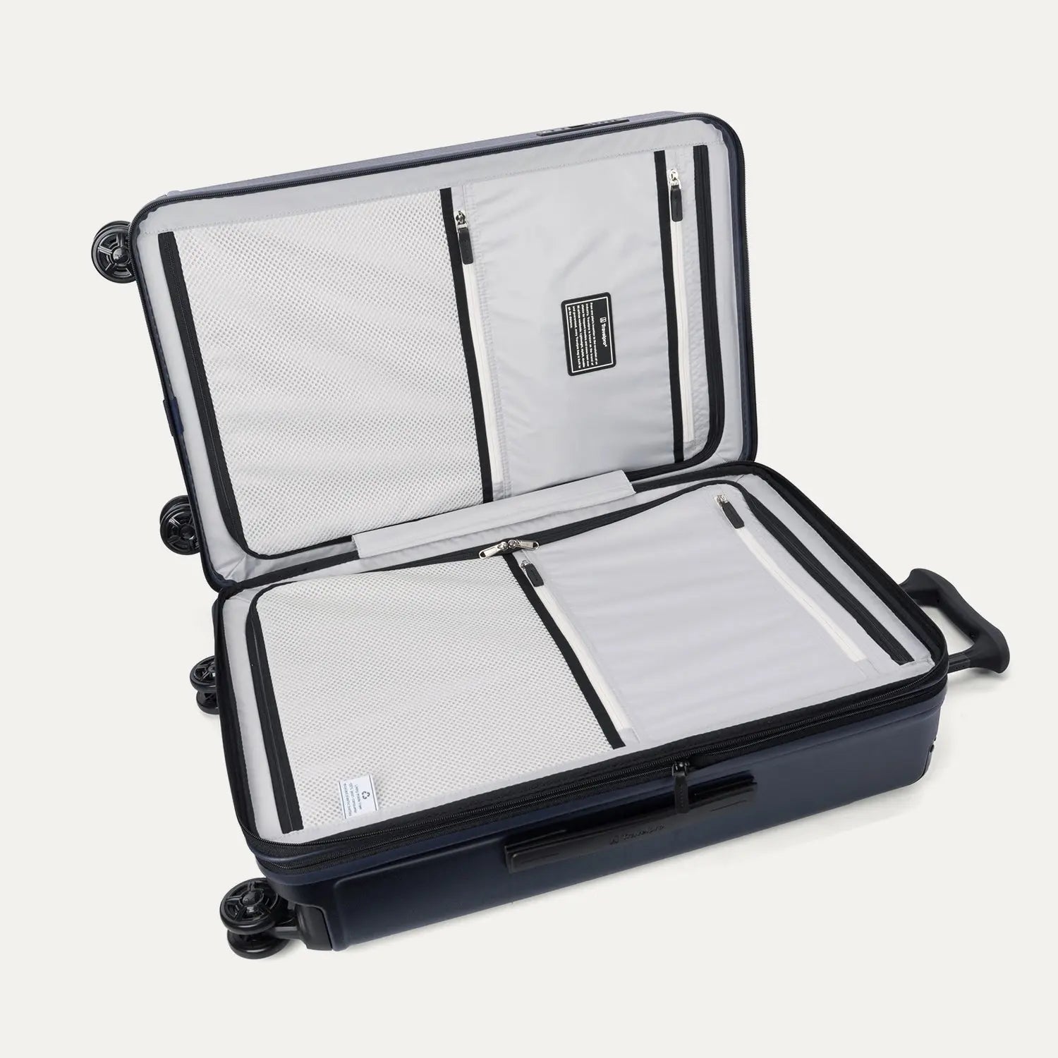 Interior packing view of the Travelpro Platinum Elite Medium Check-In Hardside Spinner in Aviator Navy, featuring dual zippered divider panels and the ECOFAB™ lining made from 100% recycled plastic bottles.