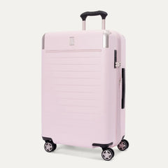 Three-quarter front view of the Travelpro Platinum Elite Medium Check-In Hardside Spinner in Powder Pink, featuring a durable polycarbonate shell with polished aluminum corner armor, an extended telescopic handle, and multi-directional wheels against a clean off-white background.