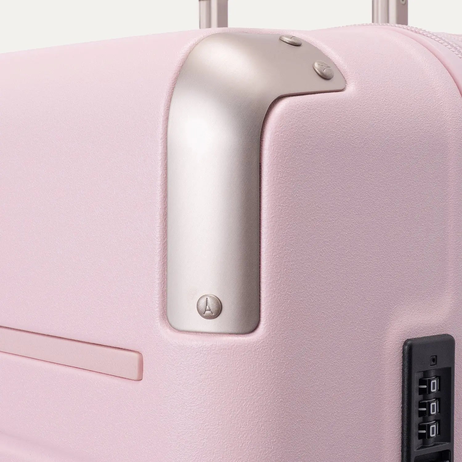 Close-up of the Travelpro Platinum Elite Medium Check-In Hardside Spinner in Powder Pink, featuring protective polished aluminum corner armor, an integrated TSA-approved combination lock, and smooth side zipper trim against a clean off-white background.