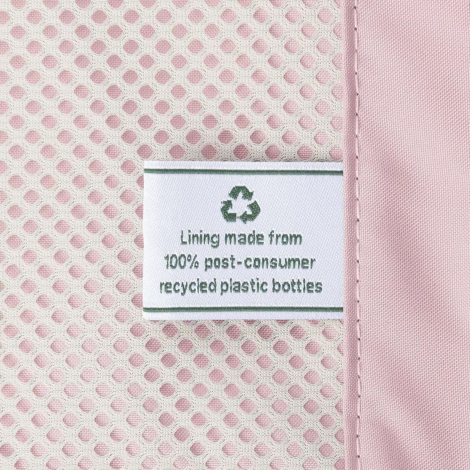 Close-up detail of the ECOFAB™ lining inside the Travelpro Platinum Elite Medium Check-In Hardside Spinner, showing a white fabric label that reads "Lining made from 100% post-consumer recycled plastic bottles" with a green recycling symbol against the pink mesh interior.
