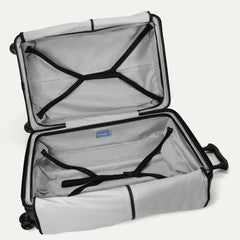 Fully open interior packing view of the Travelpro Platinum Elite Large Check-In Hardside Spinner in Jet Black, showing the spacious main compartment with adjustable hold-down straps and zippered divider panels.