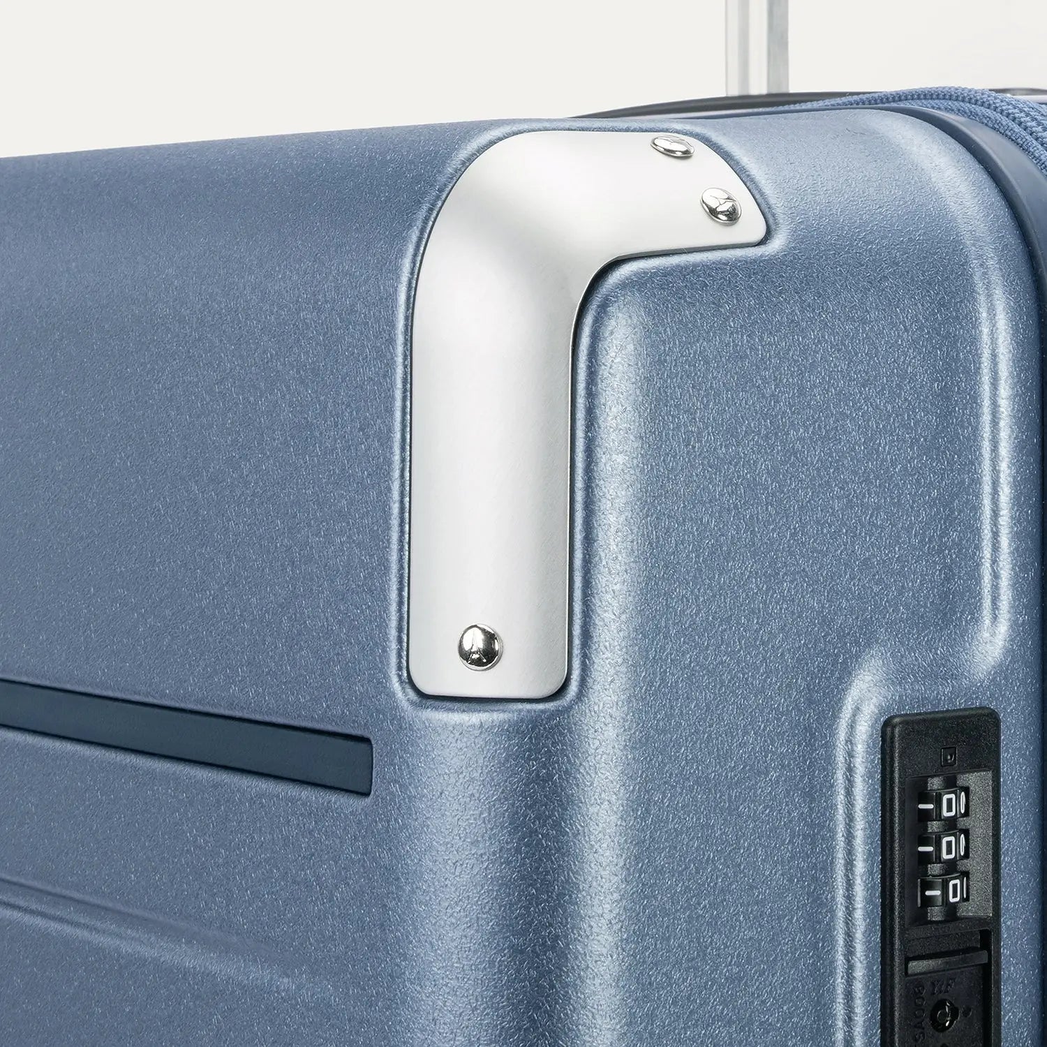 Close-up detail of the Travelpro Platinum Elite Large Check-In Hardside Spinner in Dark Sky Blue, showing the integrated TSA-approved combination lock and protective polished aluminum corner armor.