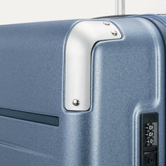 Close-up detail of the Travelpro Platinum Elite Large Check-In Hardside Spinner in Dark Sky Blue, showing the integrated TSA-approved combination lock and protective polished aluminum corner armor.
